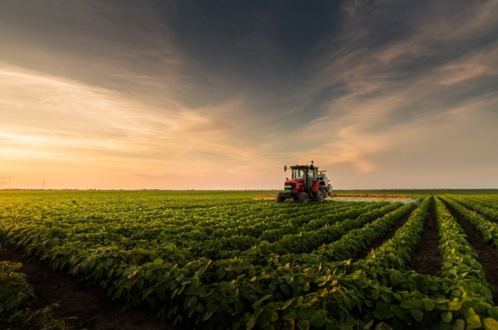 Tractor spraying pesticides on soybean field with sprayer at spring
