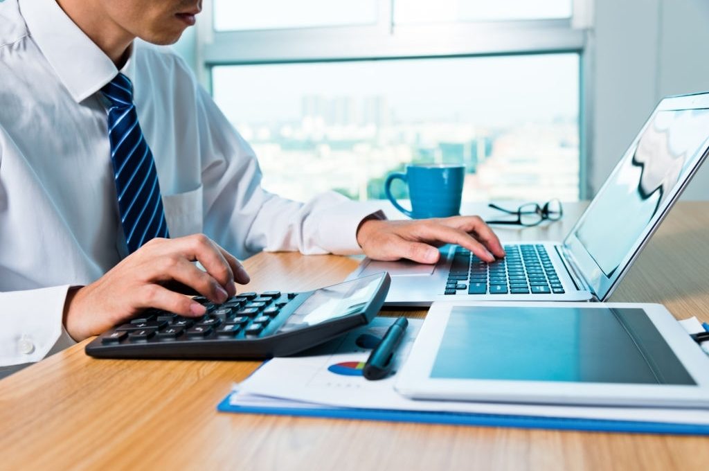 Businessman working with digital tablet and laptop in office room.